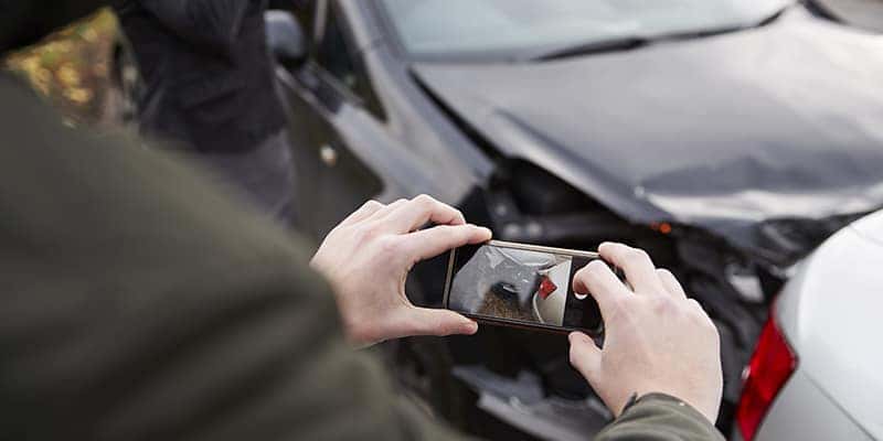 Man taking photos of car accident damage