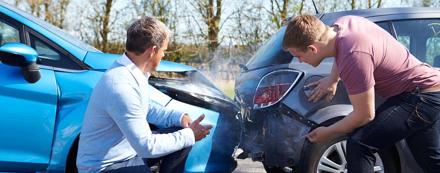 Men looking at damage from car accident