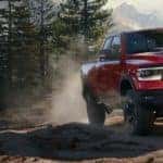 RAM 1500 driving down a dirt road through a forest