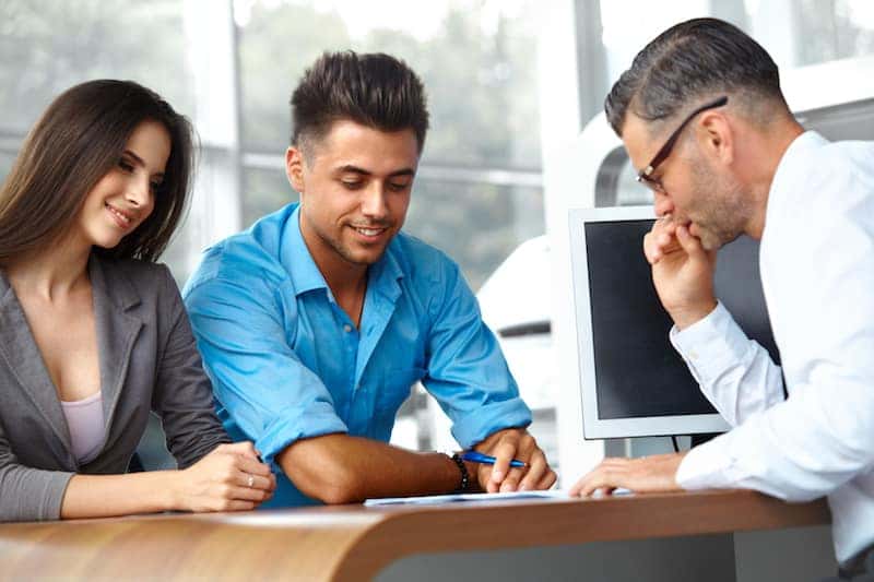 Young couple going over car sales contract with dealer