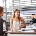 two people signing paperwork at a dealership