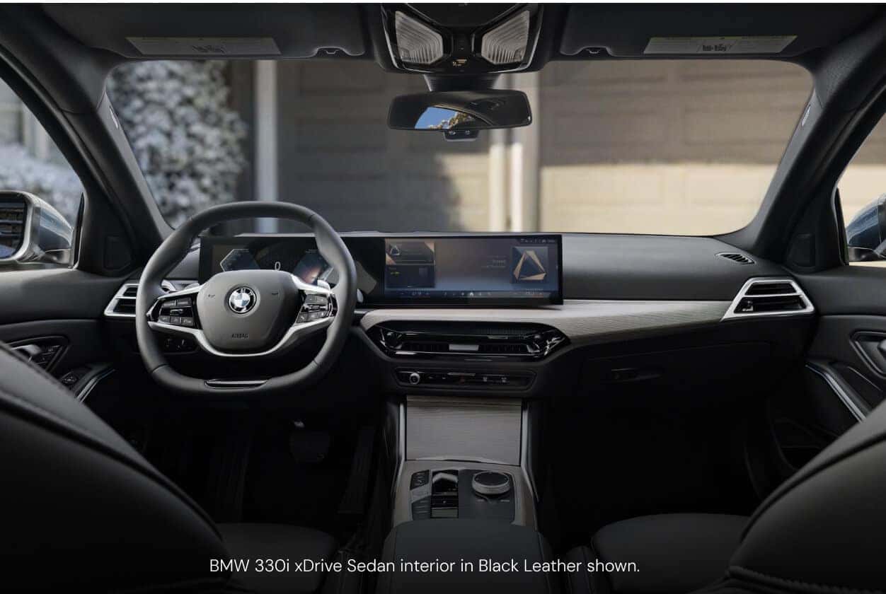 Interior cockpit view of a BMW 330i xDrive Sedan in Black Leather showcasing the curved digital display.