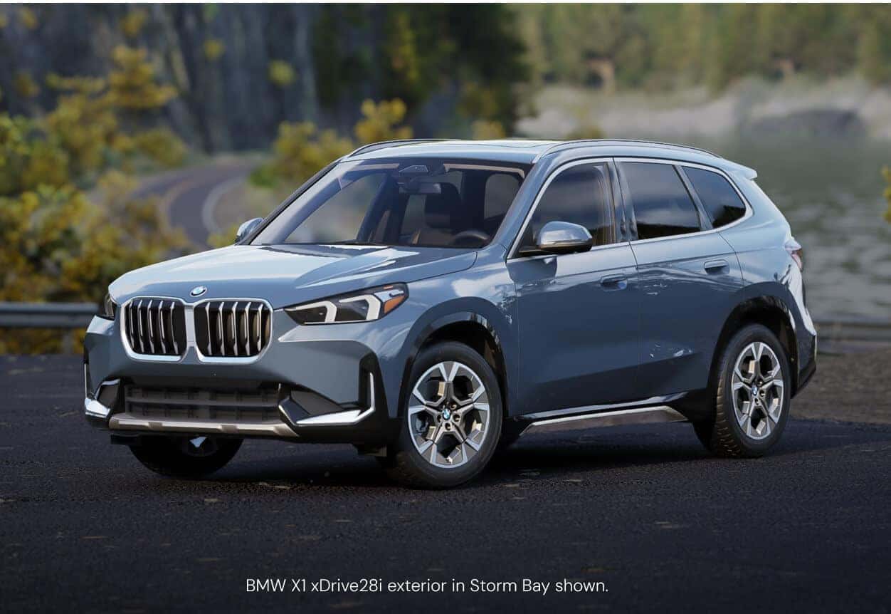Three-quarter front view of a BMW X1 xDrive28i in Storm Bay parked on a paved lot.