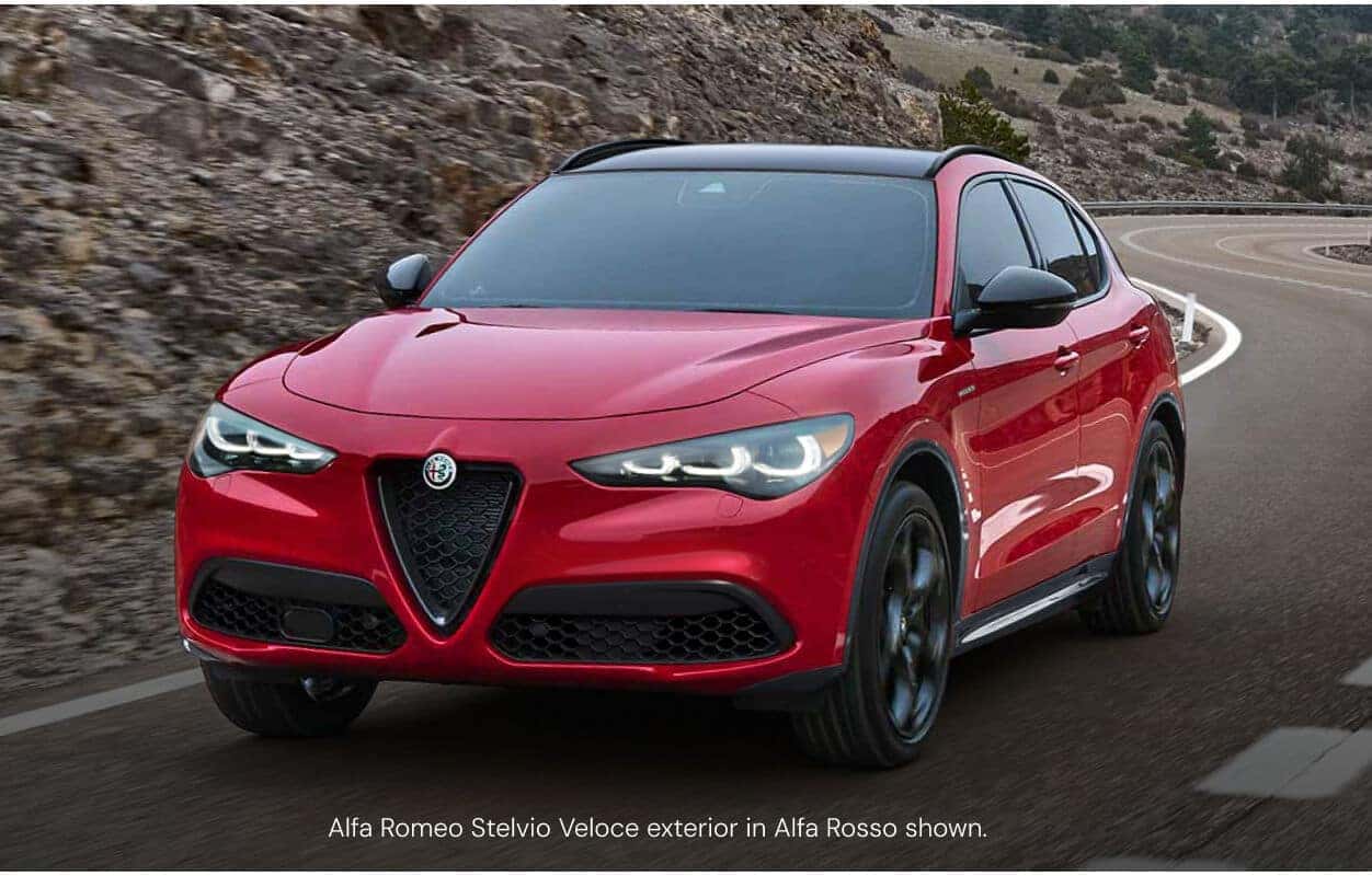 Three-quarter front view of an Alfa Romeo Stelvio Veloce in Alfa Rosso driving along a winding mountain road.