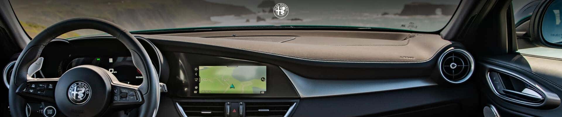 Driver seat view of the cockpit and steering wheel inside a 2026 Alfa Romeo Giulia Veloce with Black Leather interior.
