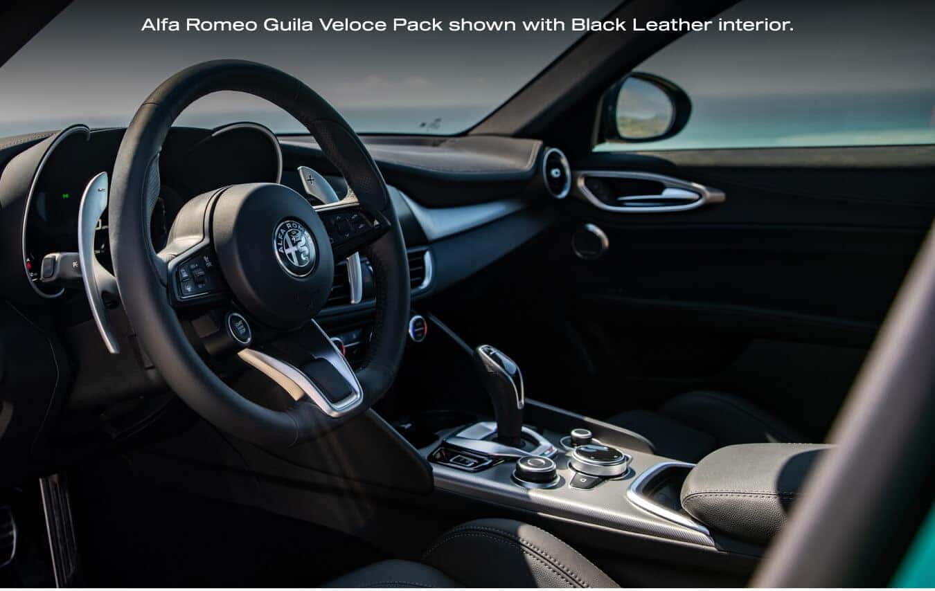 Angled interior view highlighting the steering wheel and center console of a 2026 Alfa Romeo Giulia Veloce with Black Leather interior.