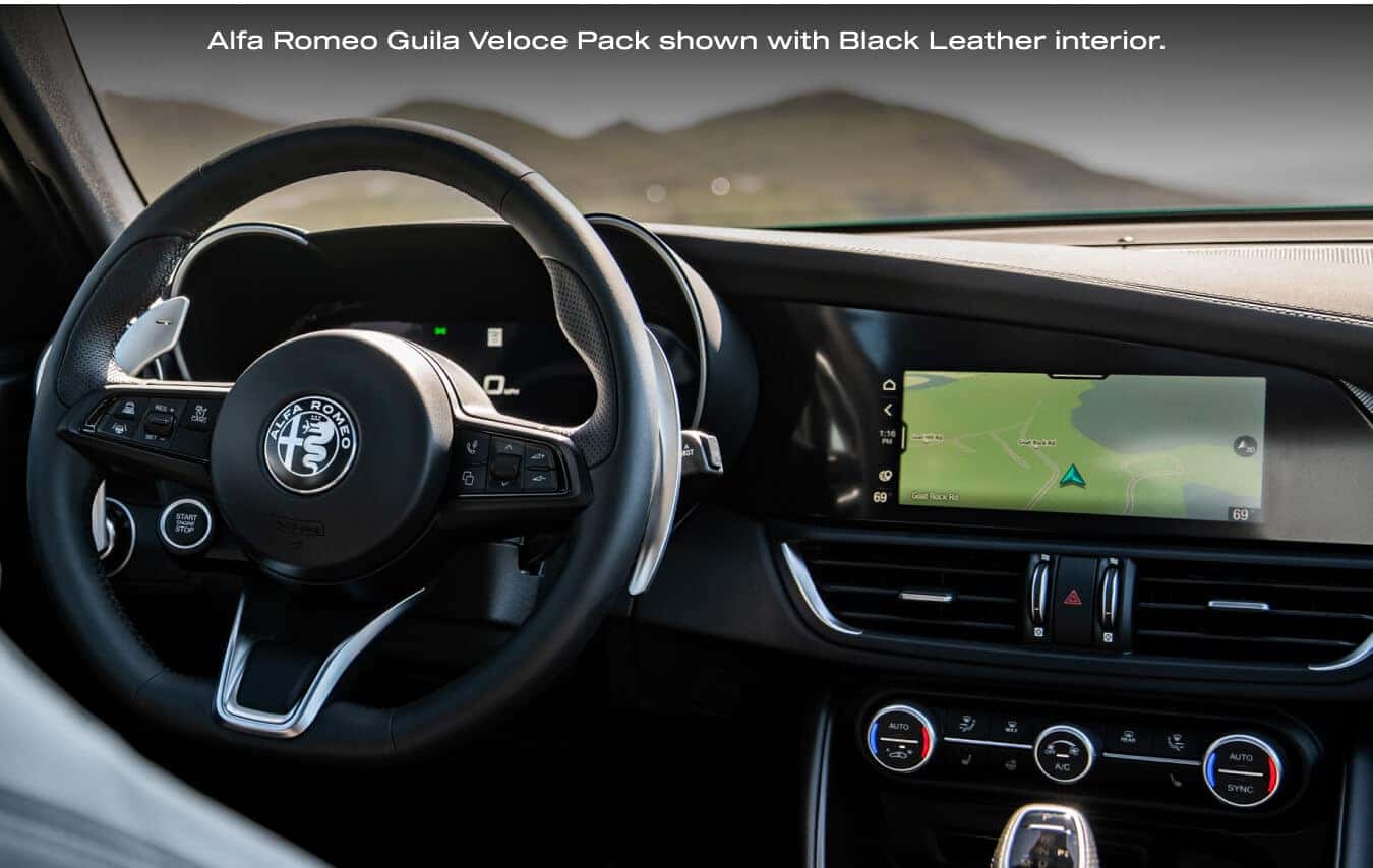 Close-up view of the steering wheel, digital display, and infotainment system in a 2026 Alfa Romeo Giulia Veloce with Black Leather interior.