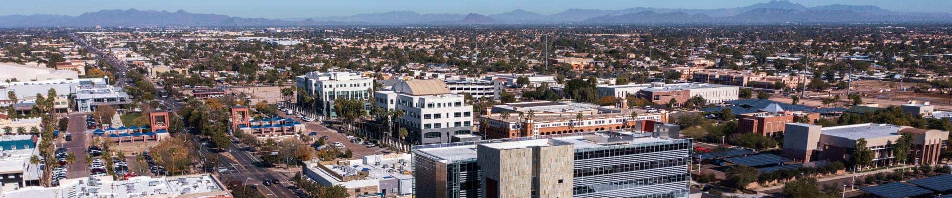 Aerial view of a sprawling urban area with commercial buildings, streets, and mountains in the distance.