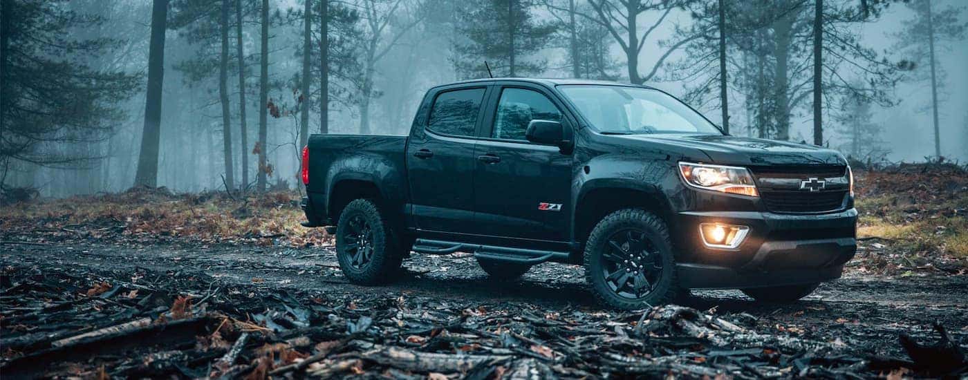 A black 2018 Chevy Colorado Z71 is shown on a trail in the woods after leaving a Chevy truck dealer near you.