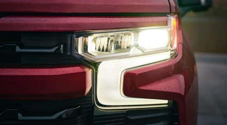 A close up shows the driver side headlight on red 2022 Chevy Silverado 1500.