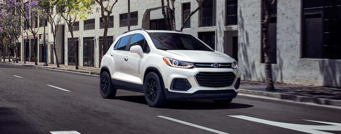 A white 2022 Chevy Trax is shown from the front driving through a city.