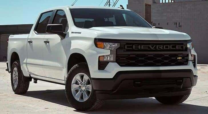 A white 2024 Chevy Silverado 1500 WT is shown parked near a Chevy Silverado 1500 Dealer.