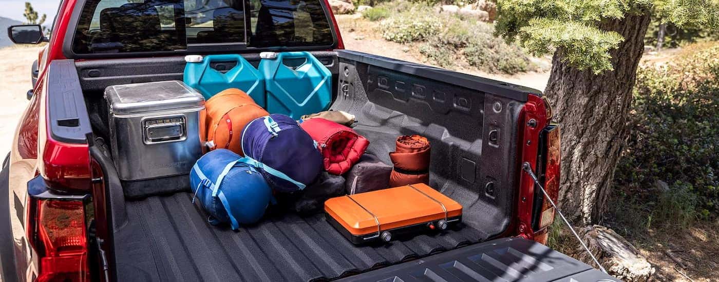 Camping gear loaded in the bed of a red 2024 Chevy Colorado Trail Boss.