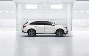 This is a white Acura MDX sitting in a showroom.