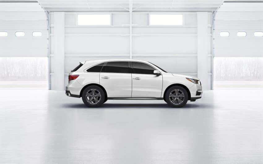 This is a white Acura MDX sitting in a showroom.
