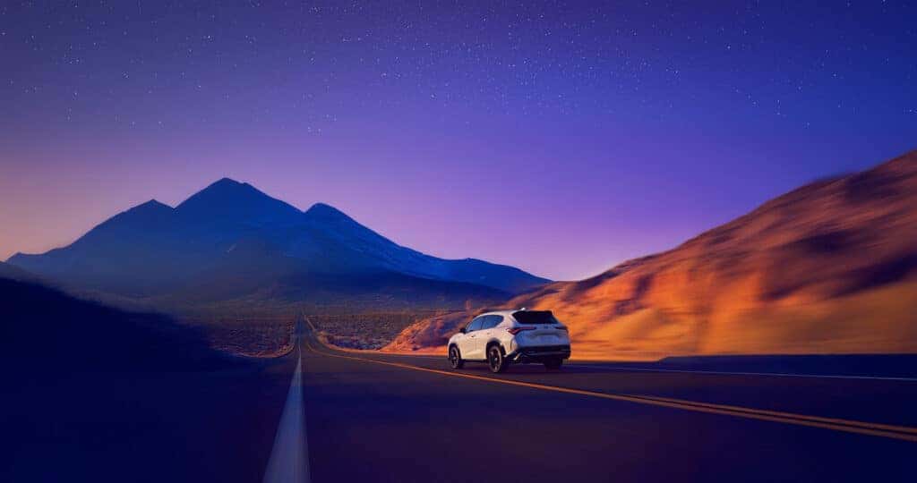 2025 Acura ADX A-Spec with Advance Package driving down a desert highway at sunset towards a distant mountain range