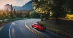 A Performance Red Pearl 2026 Acura Integra A-Spec driving through the Rocky Mountains at sunset
