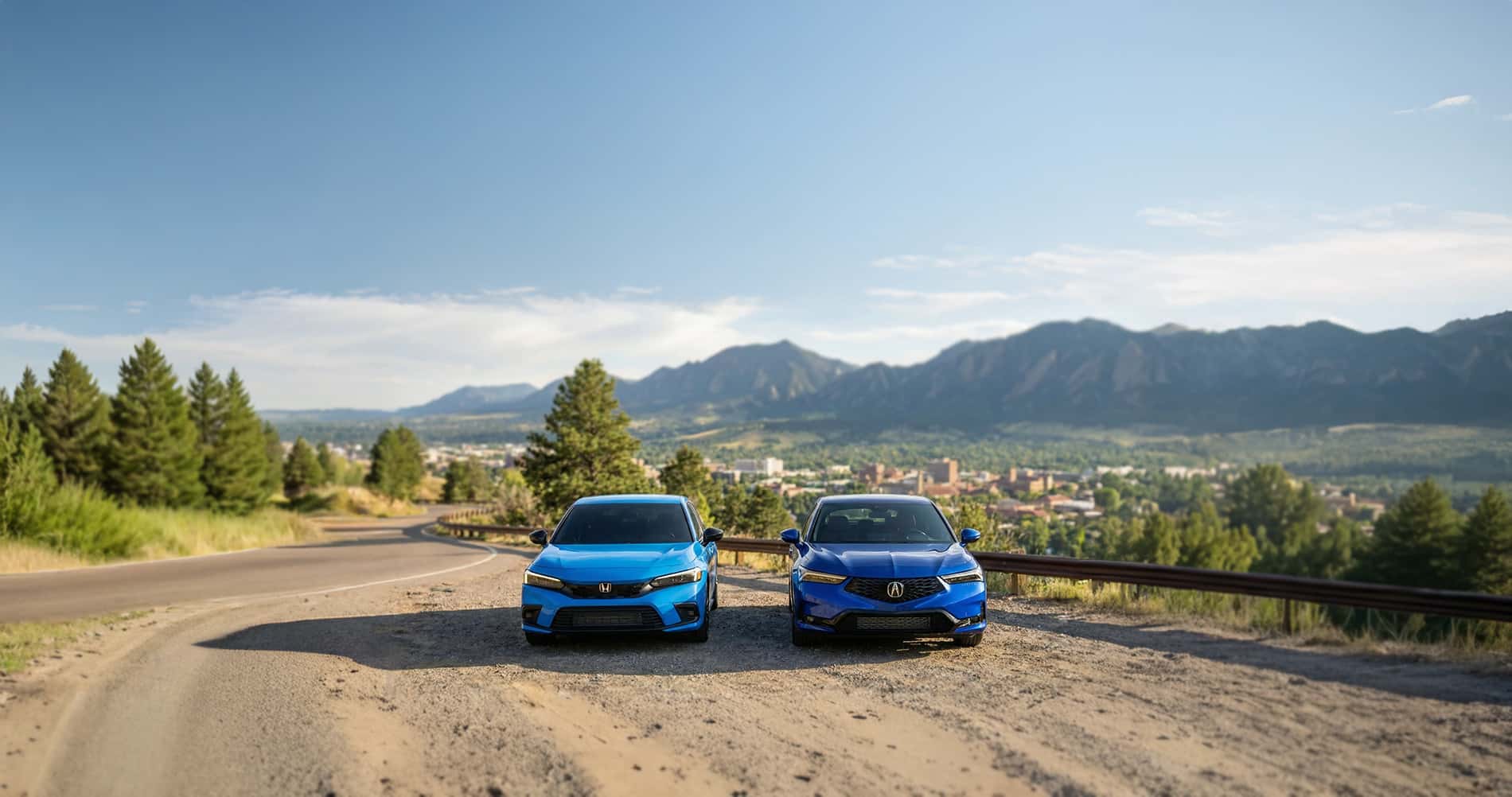 2026 Acura Integra vs Honda Civic parked on a mountain pass overlooking downtown Boulder Colorado