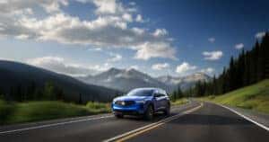 2026 Acura RDX Color of APEX BLUE PEARL driving through the Rocky Mountains