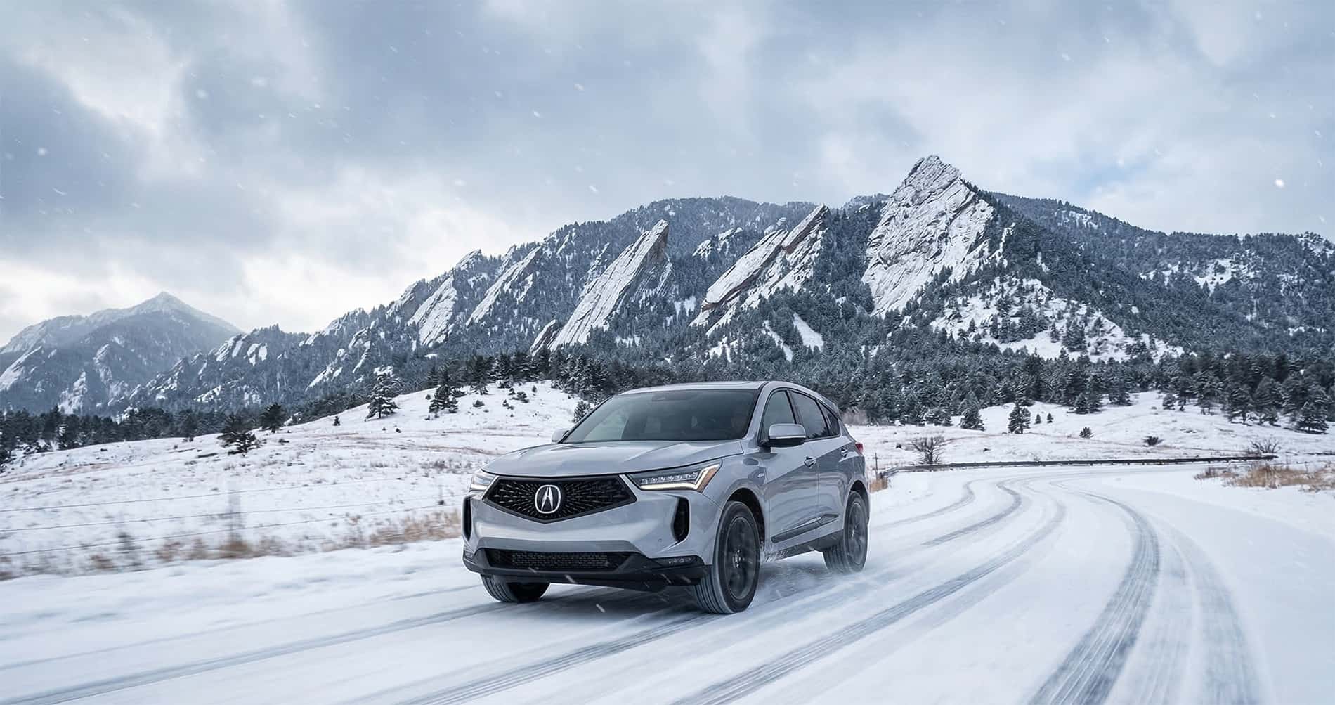 Acura SUV with SH-AWD driving on a snowy road near the Flatirons in Boulder Colorado showcasing winter traction and control