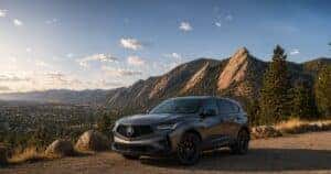 2026 Acura RDX parked at a scenic Boulder mountain overlook during golden hour, with the Flatirons rising dramatically behind it and sweeping Front Range views stretching across the background.
