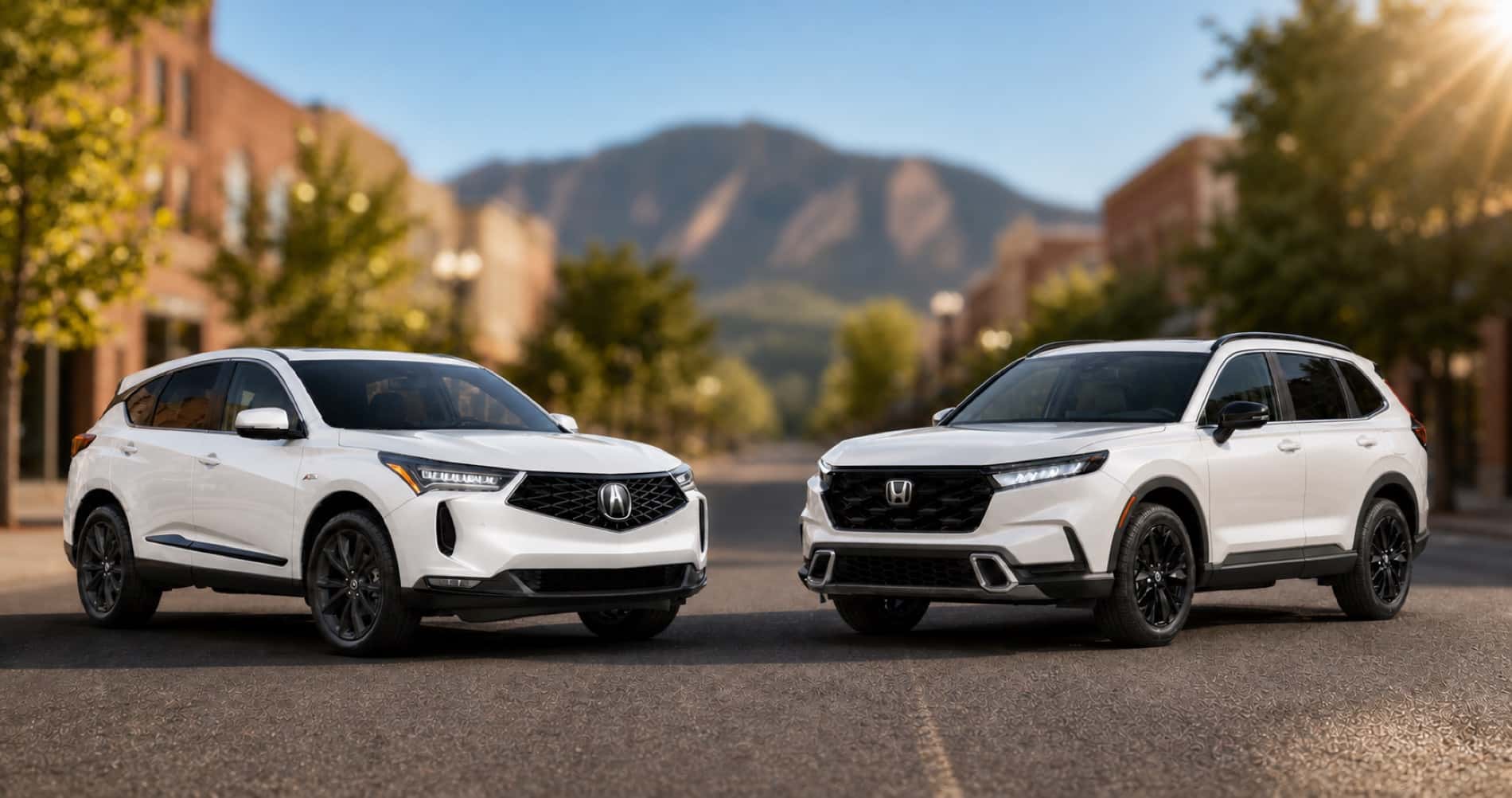 White Acura RDX and white Honda CR‑V parked on city street with mountain backdrop at sunrise showcasing front grille designs and trim level styling.
