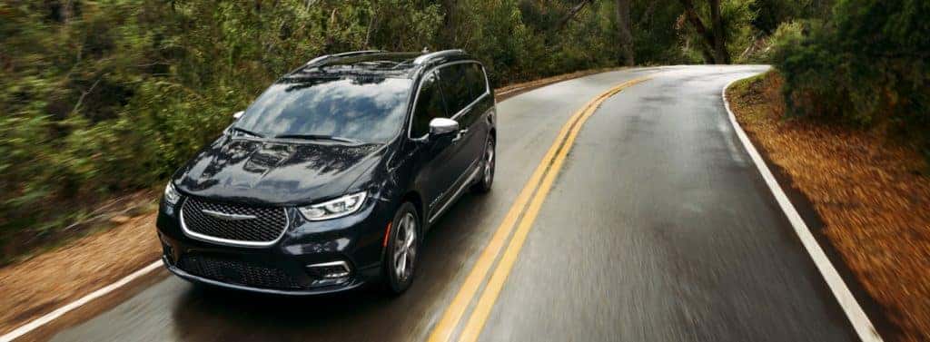 2021 Chrysler Pacifica black drives down forested road in rain