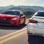 Red 2019 Toyota Camry and white 2019 Toyota Camry passing each other on mountain highway