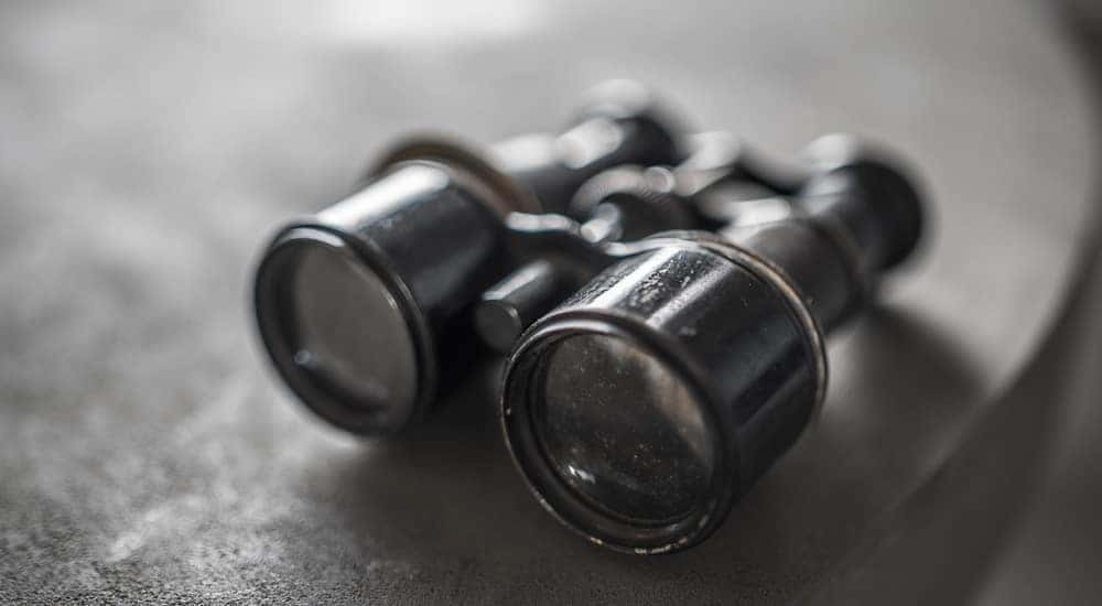 Black and white photo of binoculars sitting near the edge of a table