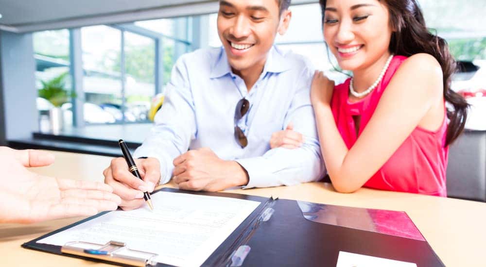 A young couple excited about signing their loan paperwork on a new car from Kings Ford Dealer in Ohio