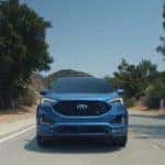 A blue 2019 Ford Edge races down an empty road