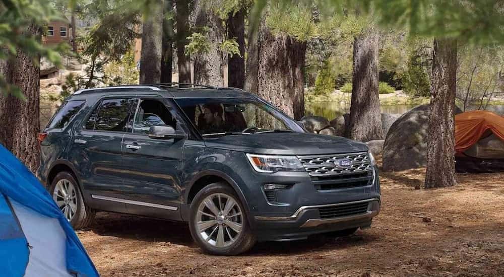 A dark gray metallic 2019 Ford Explorer on a camping trip in the woods in front of tents