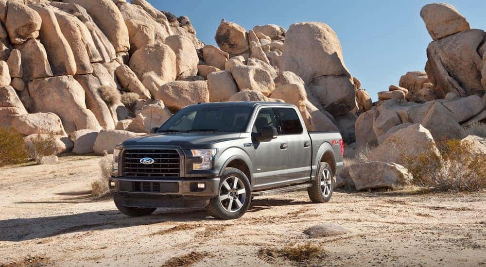 A gray 2015 Ford F150 in front of a rock pile