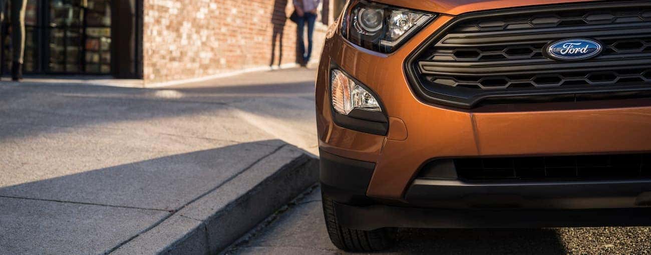 An orange 2019 Ford EcoSport sits confidently on a city street knowing that it's won the comparison of 2019 Ford EcoSport vs 2019 Chevy Trax