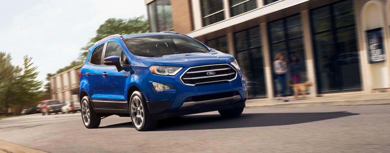 A blue 2019 Ford EcoSport drives down a city street