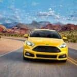 A yellow 2017 Ford Focus is driving on a road through the desert. The Focus is an option for used cars in Cincinnati.