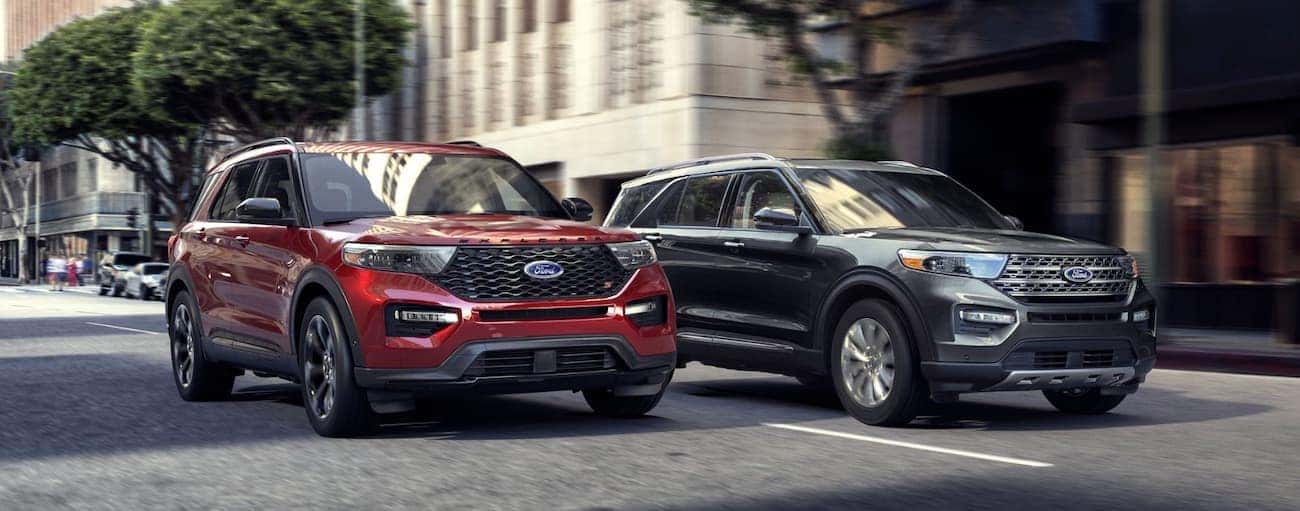 A grey and a red 2020 Ford Explorer are driving down a Cincinnati, OH city street side by side.