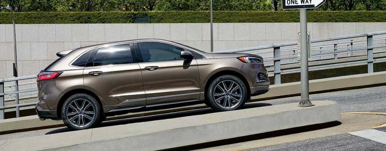 A gold 2019 Ford Edge is stopped at an intersection on a hill in Cincinnati, OH.