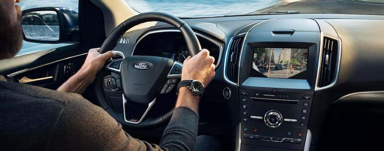 The interior of a 2019 Ford Edge is shown as the driver passes a lake outside Cincinnati, OH.