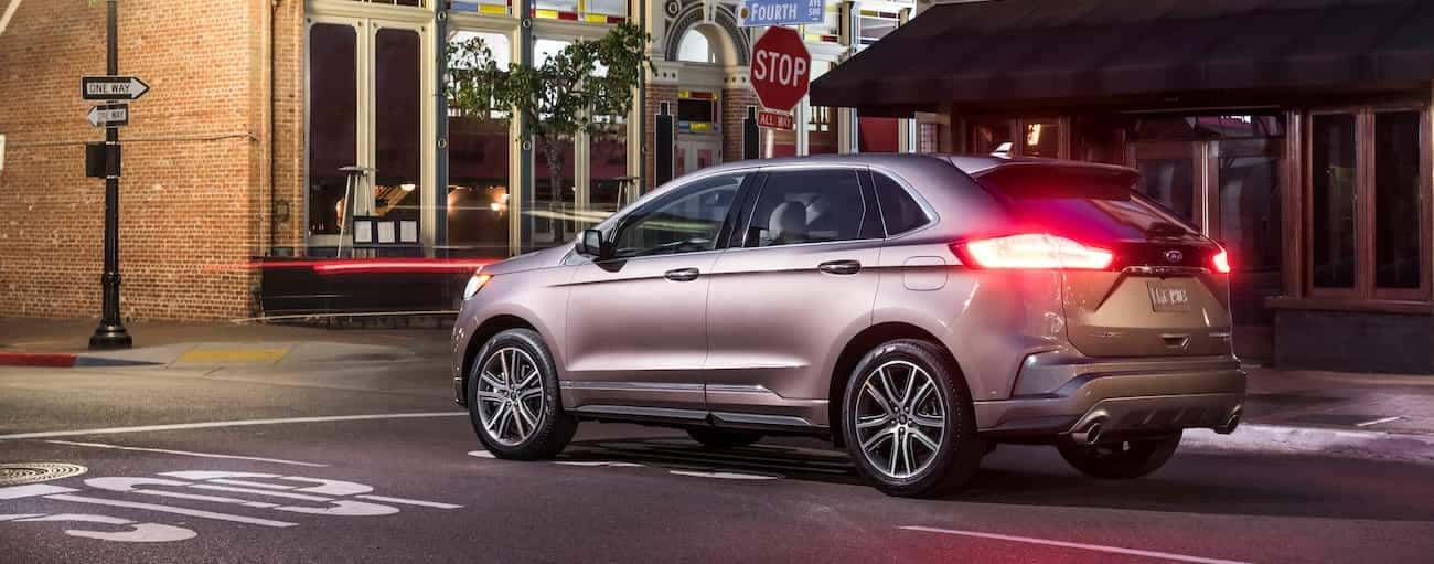 A tan 2019 Ford Edge is at an intersection near Cincinnati, OH at night.