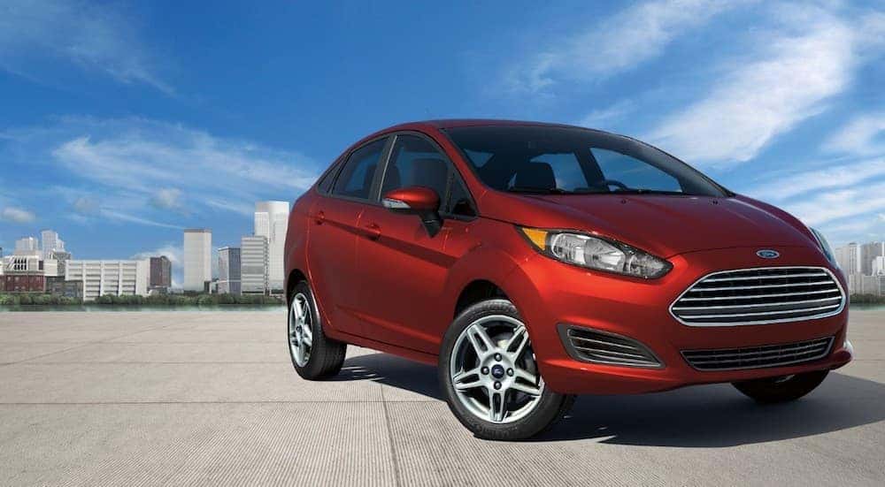 A red 2019 Ford Fiesta is parked with a city skyline in the background.