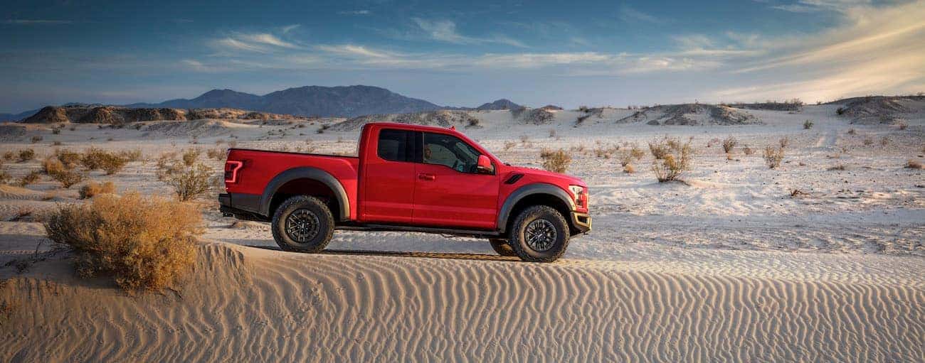 A red 2019 Ford Raptor is in the sand in a desert.
