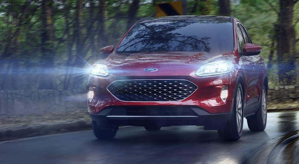 A red 2020 Ford Escape with a 1.5L EcoBoost engine is driving on a wet road in the rain near Cincinnati, OH. 