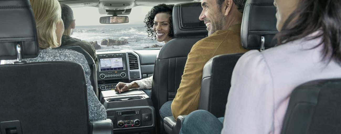 A smiling group of friends are sitting inside of a 2020 Ford Expedition.