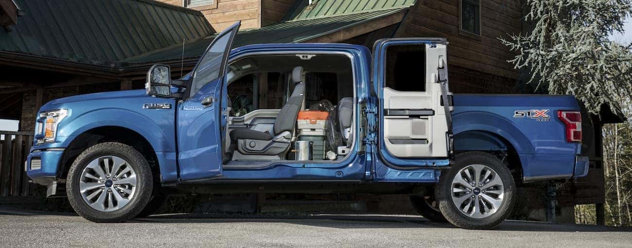 A blue 2020 Ford F-150 is parked in a driveway near Cincinnati, OH with doors open showing the interior.