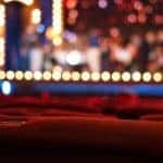 Red theater seats are shown with blurred stage lights in Cincinnati, OH.