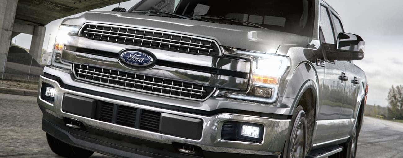 A silver 2020 Ford F-150, which wins when comparing the 2020 Ford F-150 vs 2020 Toyota Tundra, is driving under a bridge near Cincinnati, OH.