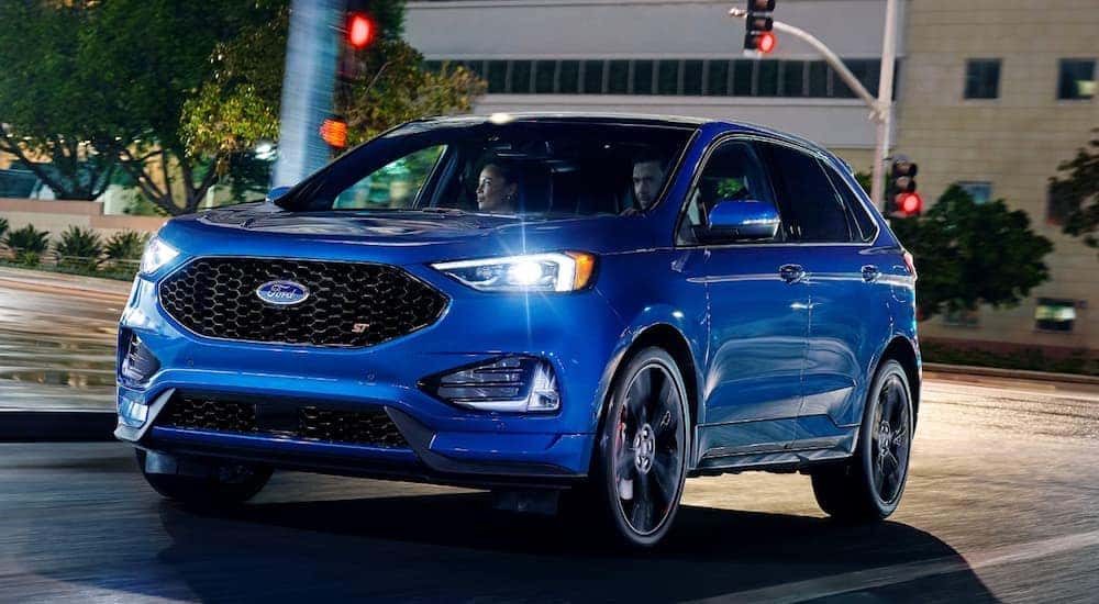 A blue 2020 Ford Edge is driving on a city street near Cincinnati, OH, at night.
