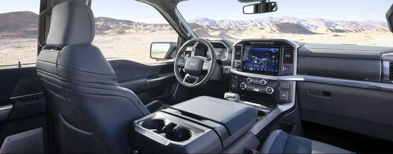 The grey interior of a 2021 Ford F-150 Raptor is shown with mountains in the windows.