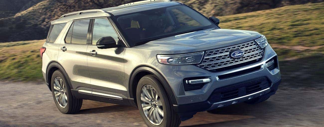 A silver 2020 Ford Explorer is driving up a hill on a dirt road.